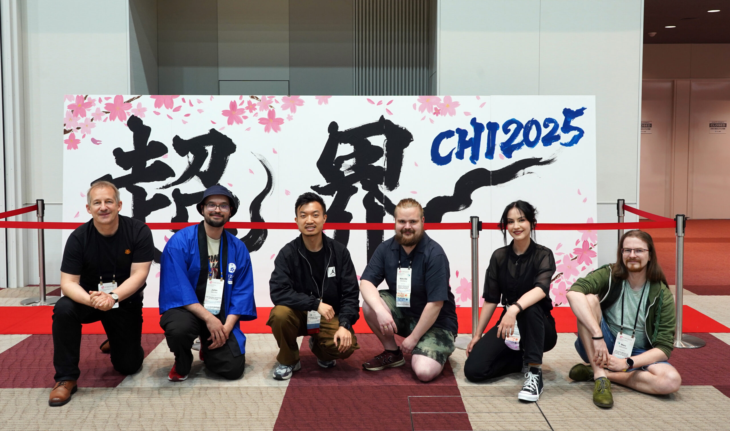 group picture of the iml team at chi 2025 in front of the conference caligraphy logo. From left to right: Raimund Dachselt, Julián Méndez, Weizhou Luo, Mats Ole Ellenberg, Katja Krug, Marc Satkowski